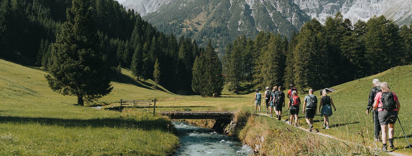 Eine Wandergruppe geht entlang eines kleinen Baches in Obernberg | © TVB Wipptal | Johannes Bitter