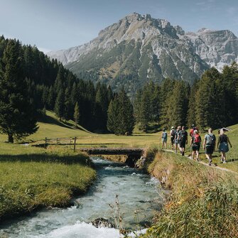 Eine Wandergruppe geht entlang eines kleinen Baches in Obernberg | © TVB Wipptal | Johannes Bitter