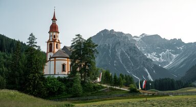 Eine Barockkirche steht auf einer leichten Anhöhung inmitten von Feldern und W | © Christoph Partsch